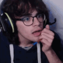 a man wearing glasses and headphones is holding a pencil in his hand .