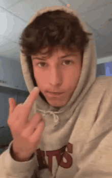 a man in a hoodie is giving the middle finger .