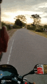 a person riding a motorcycle down a road with a oneplus phone