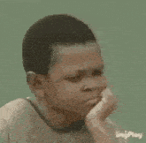 a young boy is sitting on the floor with his eyes closed and a sad look on his face .