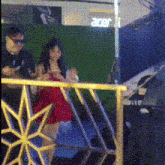 a woman in a red dress is standing next to a man in sunglasses in front of an acer sign