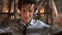 a man in a suit and tie is standing in a room with his arms outstretched and smiling .