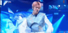 a man with pink hair is dancing on a stage in front of a blue background .