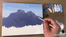 a person is painting a mountain on a canvas with the words made in animatica visible in the corner