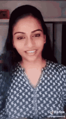 a woman is smiling and wearing a blue shirt with white flowers on it .