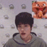 a close up of a person 's face with a stuffed animal in the background