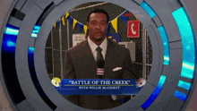 a man in a suit and tie stands in front of a sign that says battle of the creek with willie mcginest