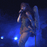 a woman with wings sings into a microphone