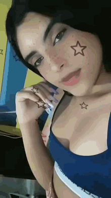 a woman with stars on her face and a blue top that says calvin klein