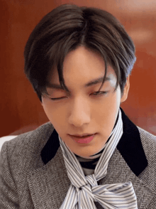 a close up of a person 's face with their eyes closed and a striped scarf around their neck