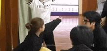 a group of people are standing in a hallway and a man is kicking a woman .