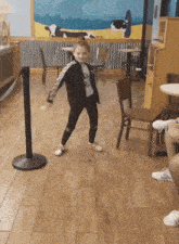 a little girl wearing a shirt that says " ua " is dancing in a restaurant