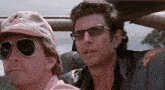 two men are sitting in a car and one has a hat that says jurassic park