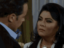 a man and a woman are looking at each other and the woman is wearing a silver necklace