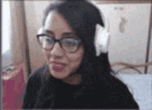 a woman wearing glasses and headphones is smiling in a room .
