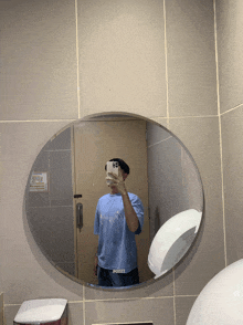 a person taking a picture of themselves in a bathroom mirror with a shirt that says poezi on it