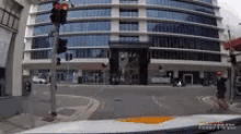 a car is driving down a street in front of a tall building