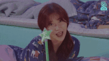 a woman is laying on a bed holding a wand .