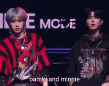 two young men are standing next to each other and one of them is holding a guitar and the other is saying bambi and minnie .