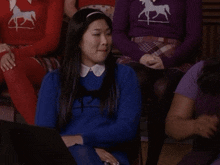 a woman wearing a blue sweater with a horse on the back