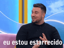 a man with a beard is sitting on a pink couch with the words eu estou estarrecido written on the bottom