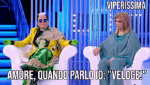 a man in a yellow jacket sits next to a woman in a green outfit with viperissima written on the bottom