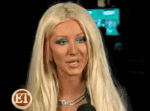 a woman with long blonde hair is talking into a microphone with a et logo in the background