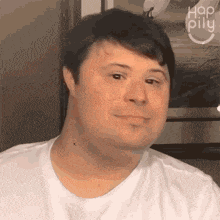 a man with down syndrome is wearing a white shirt and smiling .