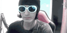 a man wearing sunglasses and a beanie is sitting in a chair