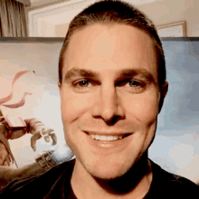 a man smiles in front of a picture of a robot