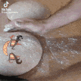 a person is kneading a ball of dough with a drawing of a dragon on it