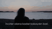 a silhouette of a woman looking out over a body of water with the words " inciler olana kadar kalsaydin bari " below her