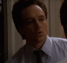 a man in a white shirt and tie is looking at himself in a mirror