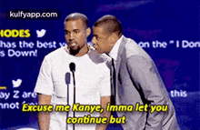 two men are standing in front of microphones and one of them is talking to the other .