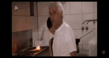 a man in a white shirt is standing in a kitchen .