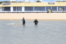 two people are standing in the water with their arms outstretched in front of a building that says ' sydney ' on it