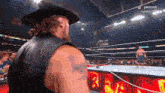 a man in a cowboy hat stands in a wrestling ring