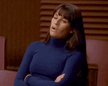a woman in a blue turtleneck with her eyes closed