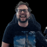 a man with glasses and a beard is singing into a microphone while wearing a shirt with a sailboat on it