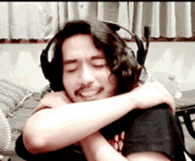 a man wearing headphones and a black shirt is hugging someone