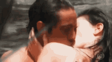 a man and a woman are kissing in the water with the letters o on the bottom right