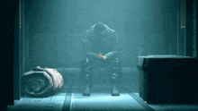 a man sits in a dark room with his head on his hands