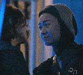 a woman wearing a hijab looks at another woman in a blue light