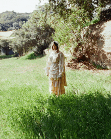 a woman in a white dress stands in a field