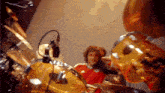 a man in a red shirt is playing drums in a band