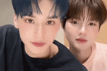 two young men are looking at the camera and one has blue hair