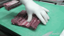 a person wearing white gloves is holding a piece of meat on a green cutting board