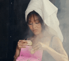 a woman with a towel wrapped around her head holds a pink bag
