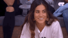 a woman wearing a white t-shirt with the letter c on it smiles for the camera
