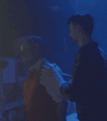a man is hugging another man in a blue light
